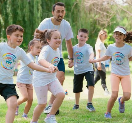Children joyfully running and holding hands in a sunny park, enjoying outdoor recreation.