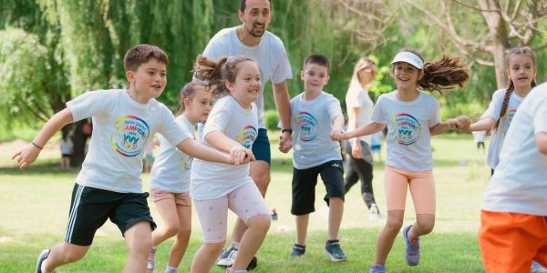 Children joyfully running and holding hands in a sunny park, enjoying outdoor recreation.
